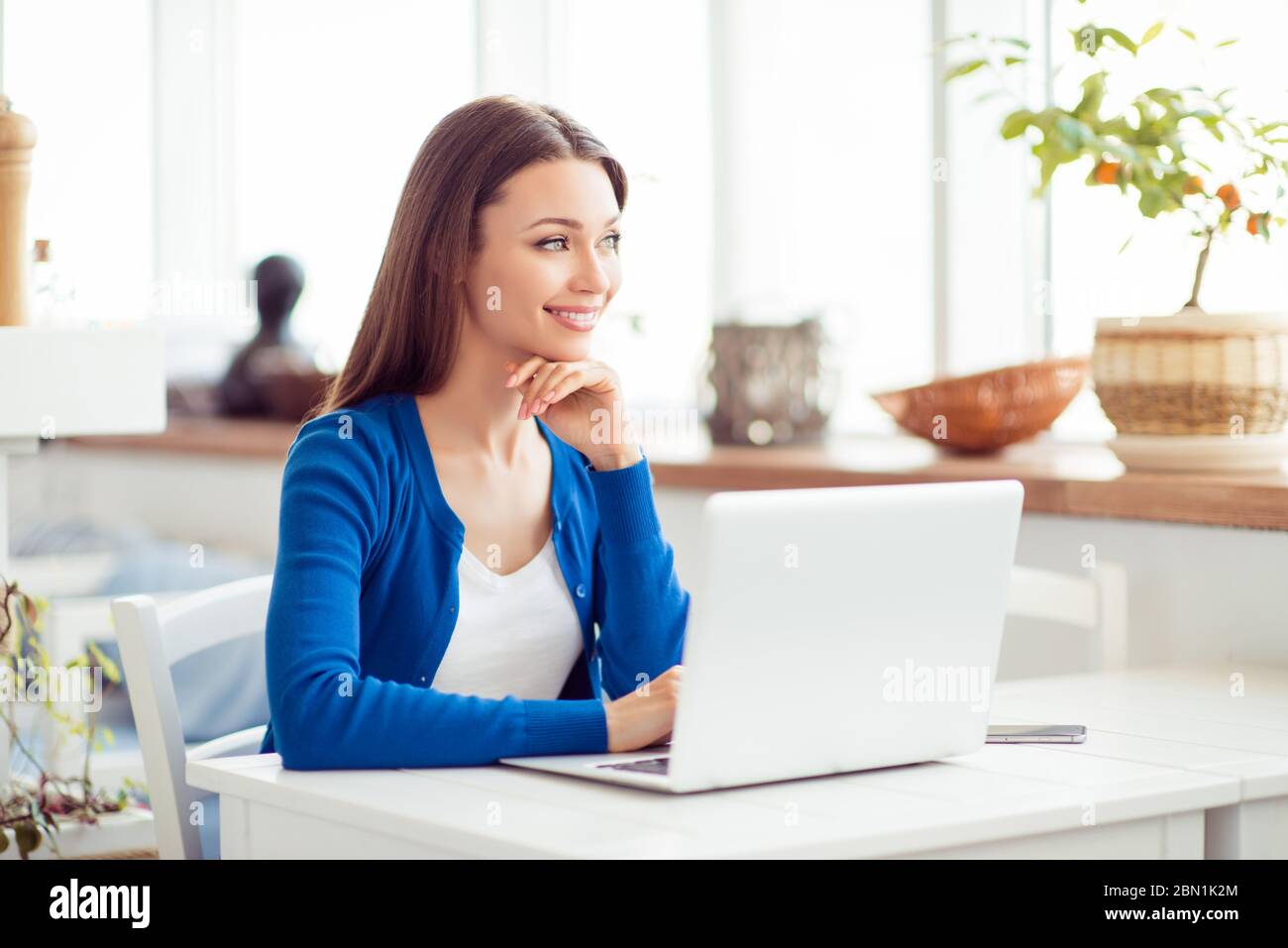 Young attractive lady is dreamy, browsing on her laptop in the cafe ...