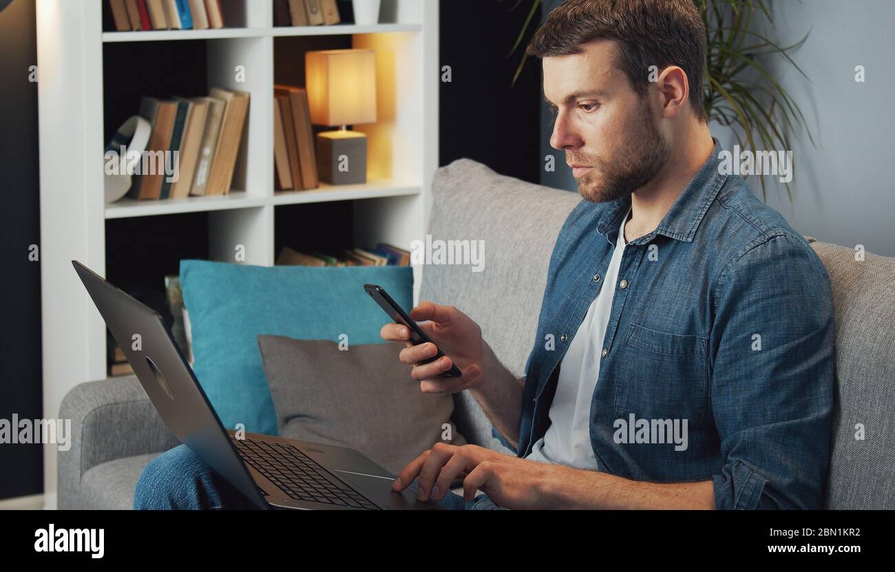 Man using phone and laptop Stock Photo