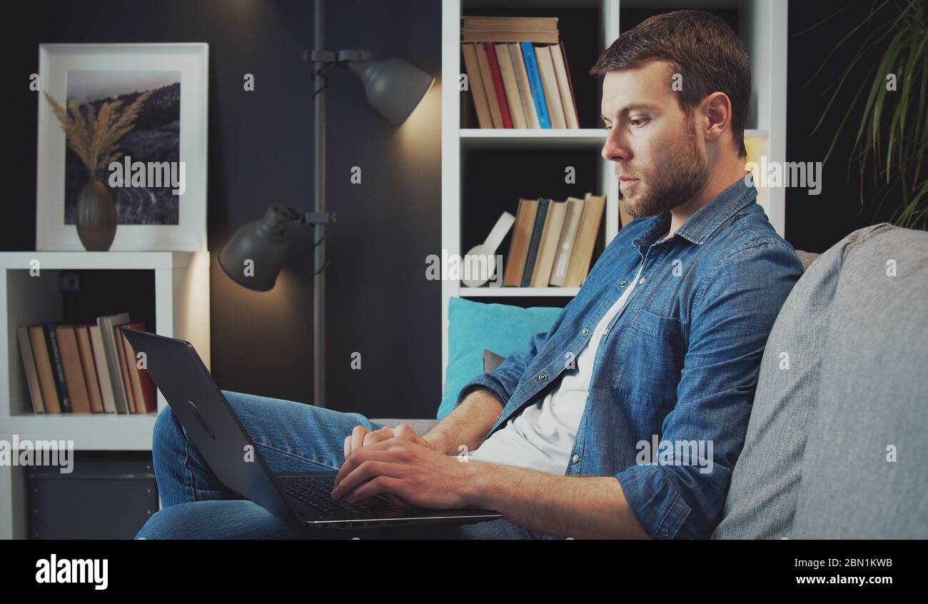 Man using laptop sitting sofa Stock Photo