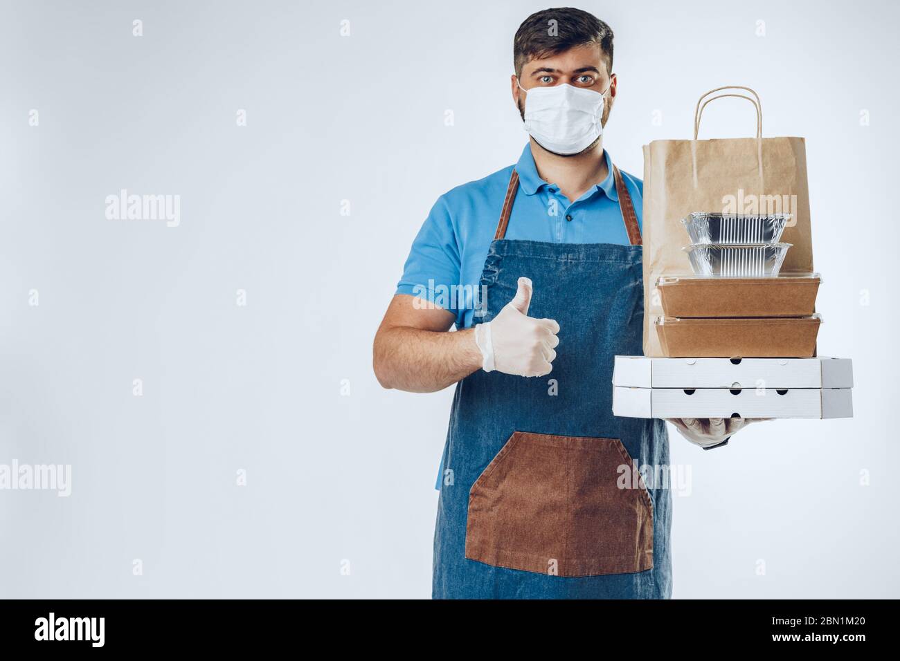 Delivery man in protective mask and medical gloves holding takeaway ...