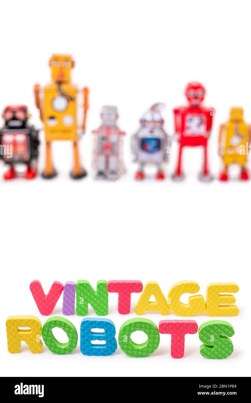 Close up view of colorful mixed vintage tin robot toys collection with foam lettering. Stock Photo