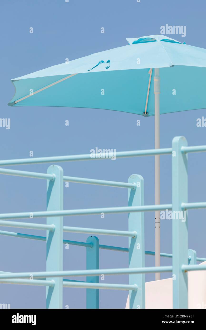 A blue beach umbrella with railings in Viareggio, Tuscany, Italy. Stock Photo