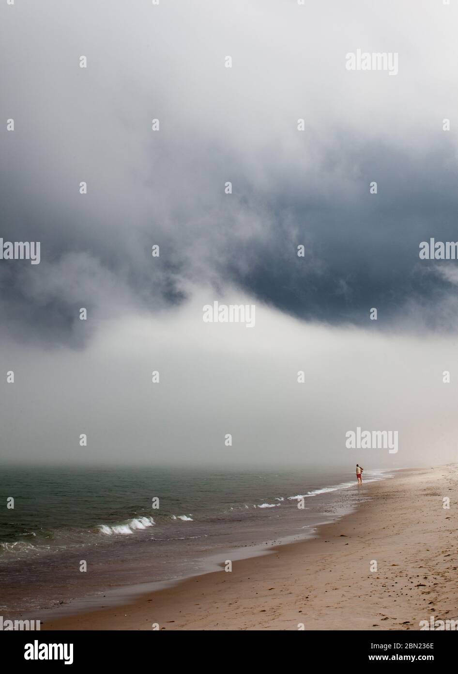 Low clouds and fog hang ominously over the shore at a beach in Duxbury, MA, USA Stock Photo