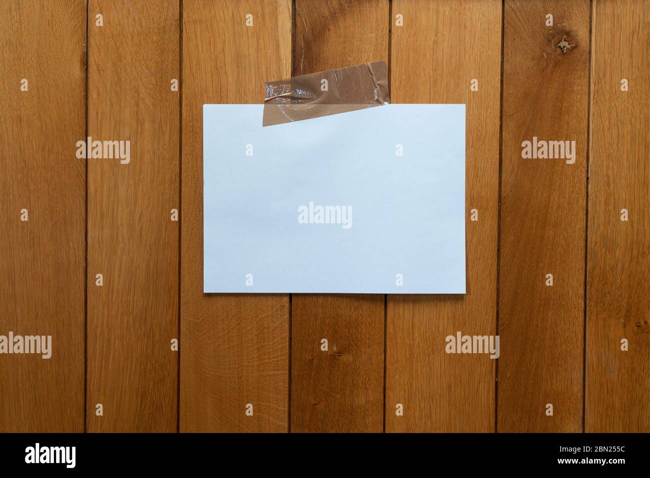a white sign hanging with tape on a wooden wall Stock Photo
