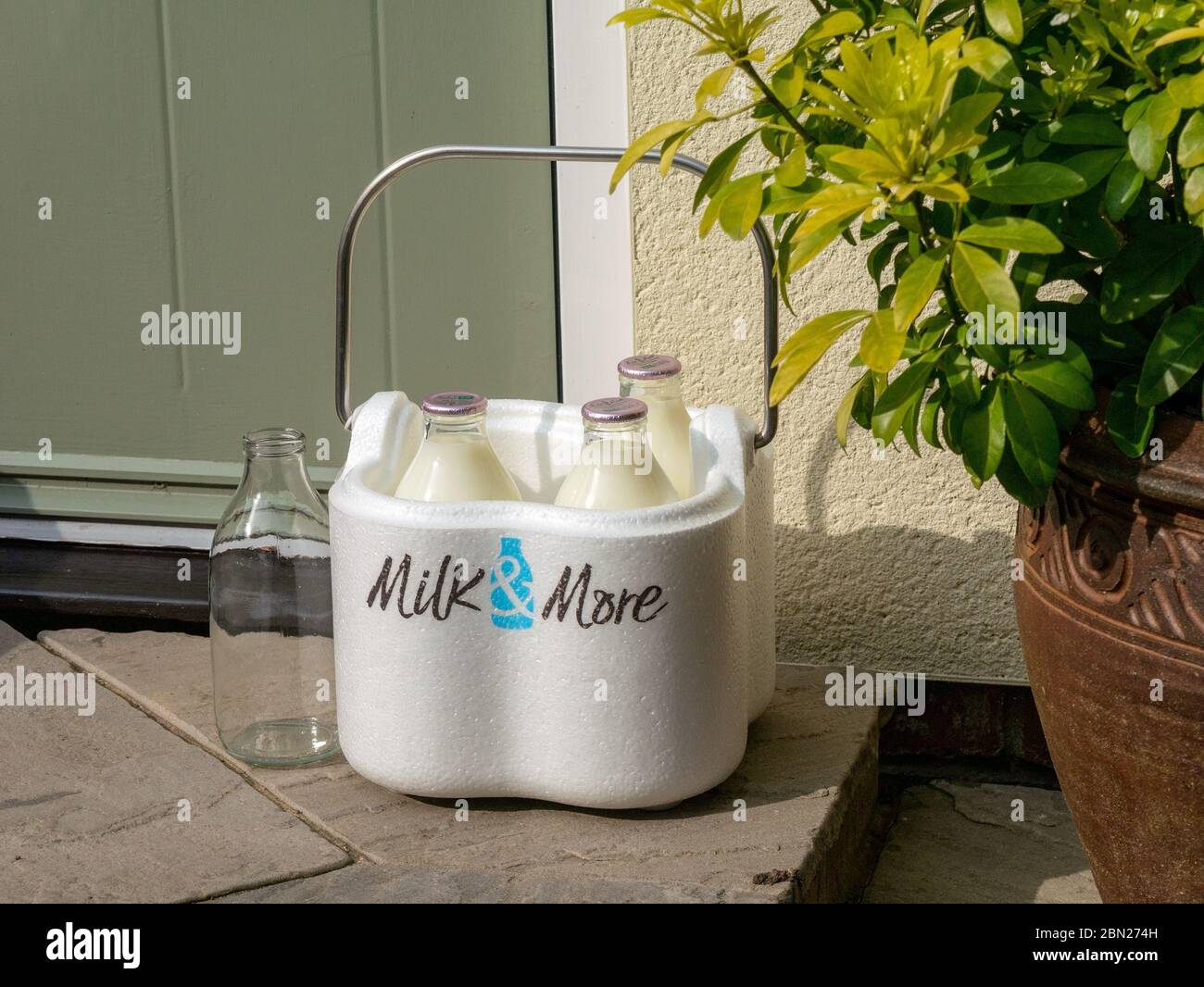 Demand for Milk and More home delivery service grows during coronavirus lockdown. Image shows milk bottles with Milk & More delivery box on doorstep Stock Photo