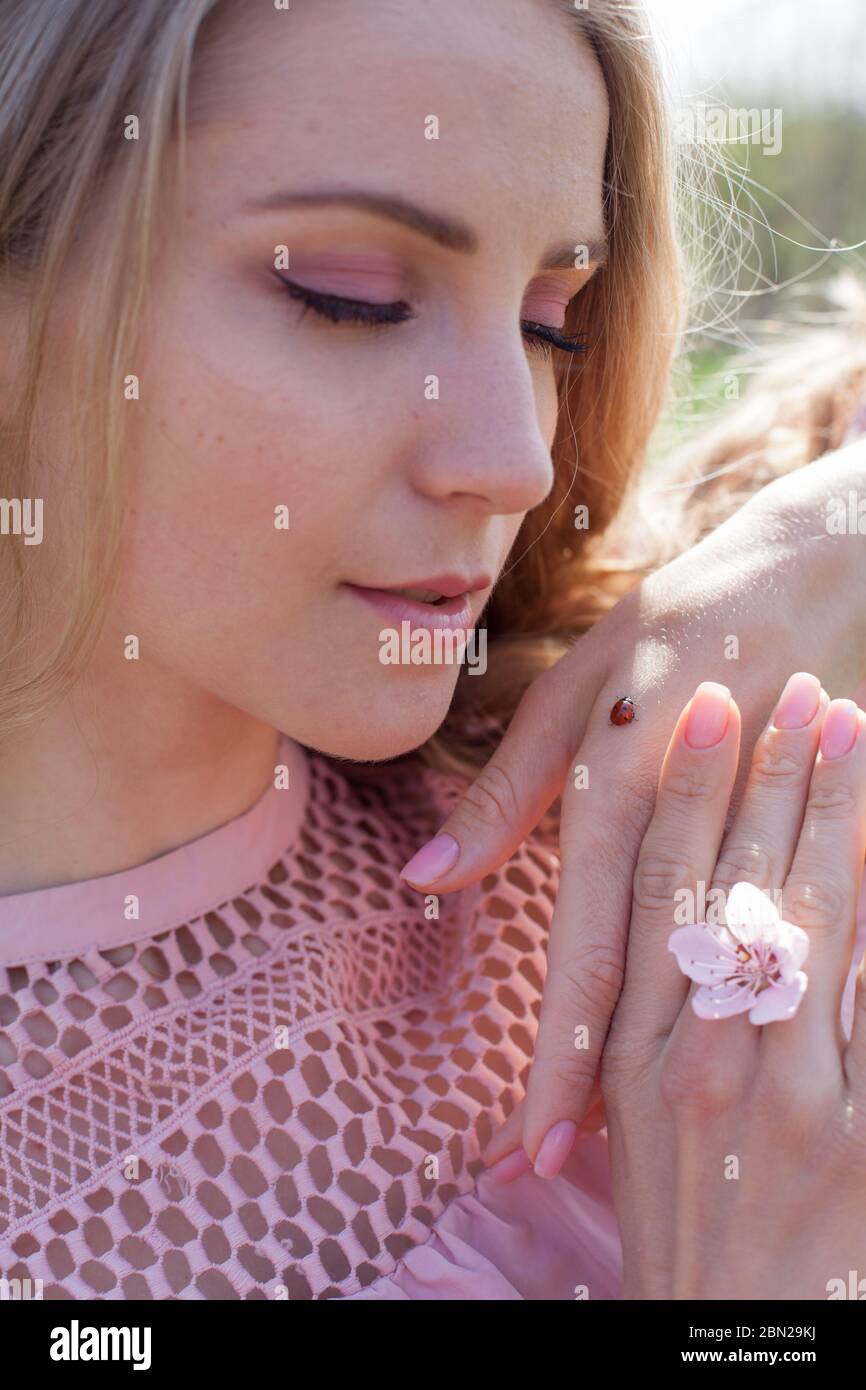 Beautiful blonde woman in pink dress and ladybug insect Stock Photo