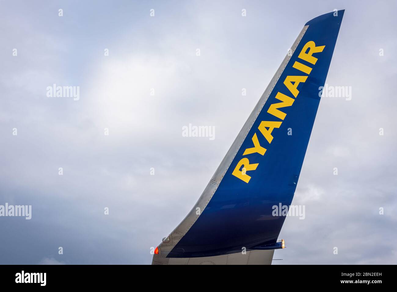 View of a grounded Ryanair plane wing with yellow and blue logo in an airport runway. Stock Photo