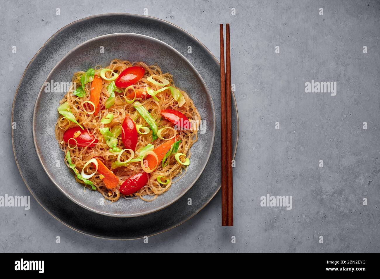 Veg Pad Woon Sen or Thai Glass Noodle Stir-Fry or Pad Thai in bowl on gray concrete backdrop. Vegetarian Pad Woon Sen is a Thai dish of glass bean noo Stock Photo