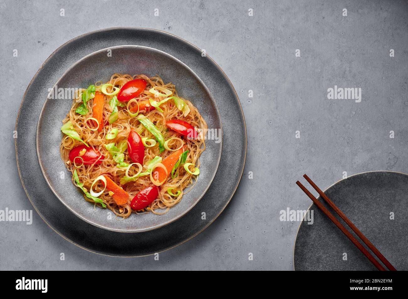 Veg Pad Woon Sen or Thai Glass Noodle Stir-Fry or Pad Thai in bowl on gray concrete backdrop. Vegetarian Pad Woon Sen is a Thai dish of glass bean noo Stock Photo