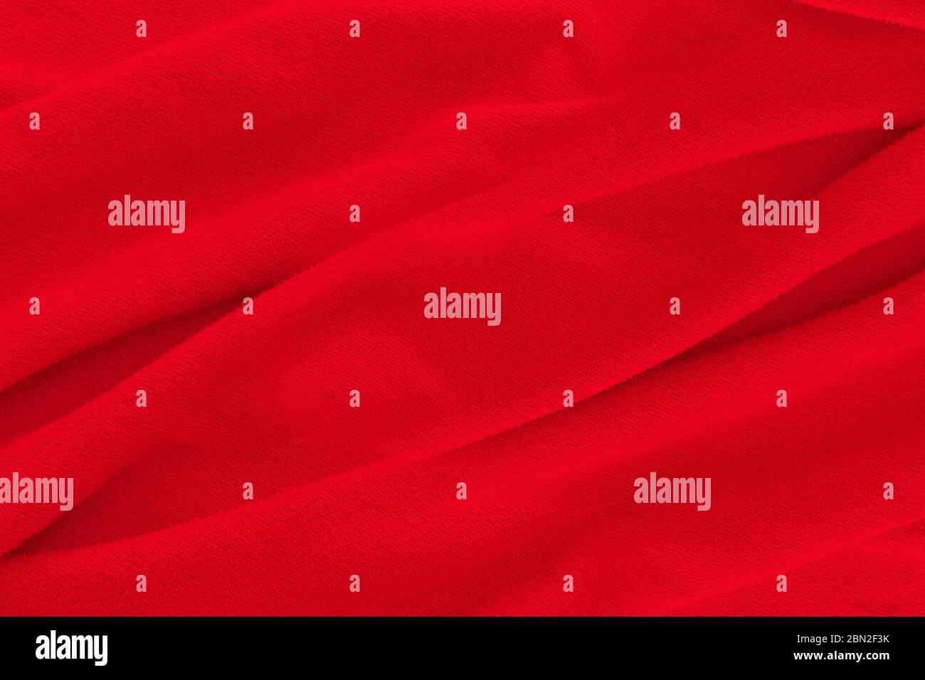 Red fabric texture background. Abstract cloth backdrop with soft waves. Stock Photo