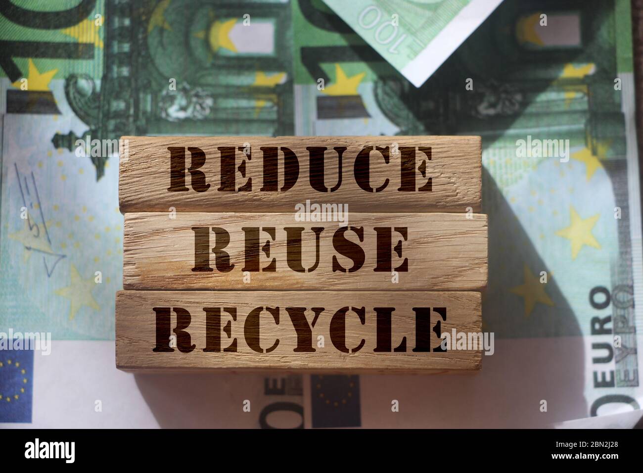 Reduce, reuse and recycle words on wooden blocks laying on banknotes of ...