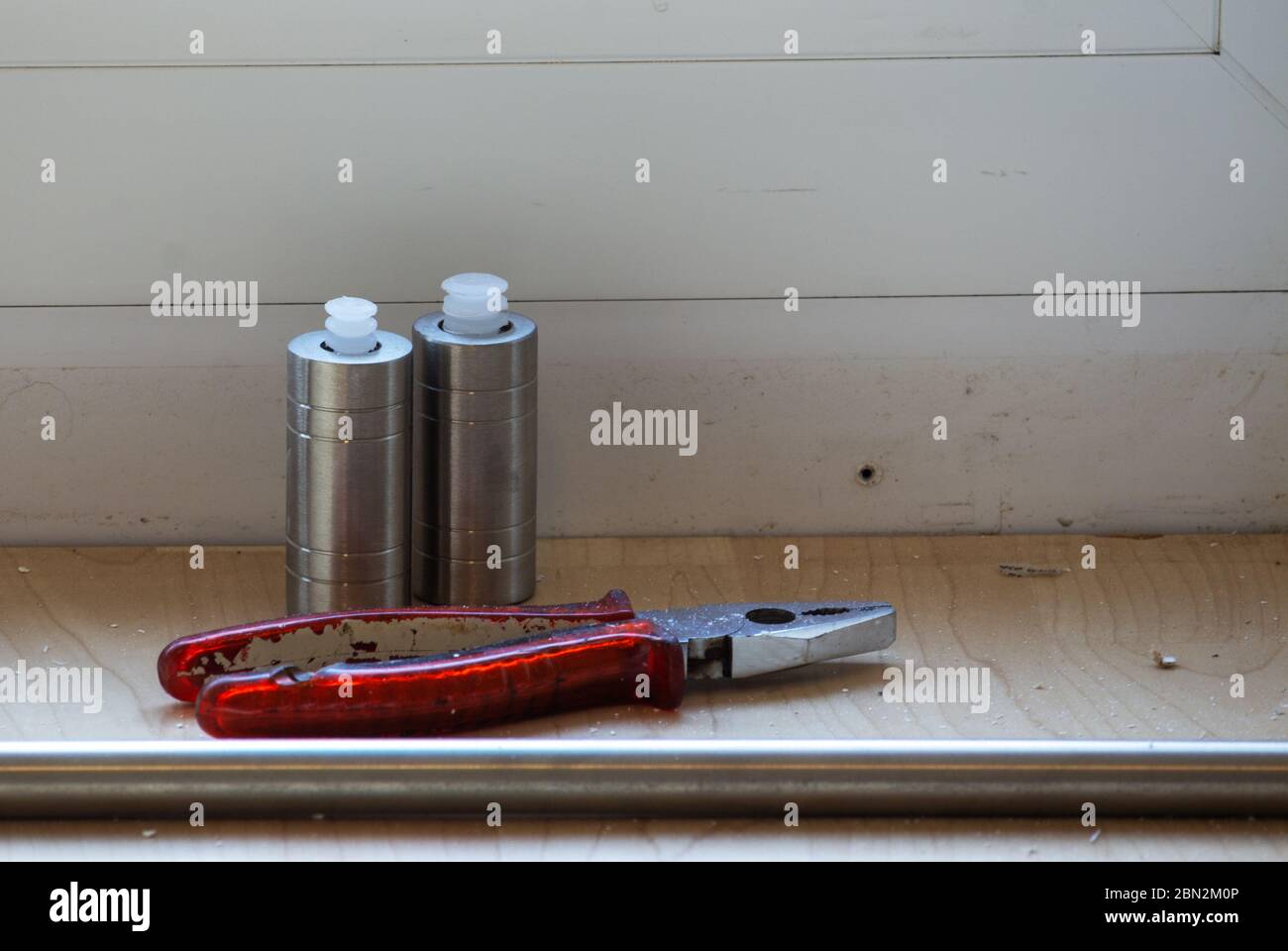 End caps of a curtain rod in front of the window frame, in front of it a combination pliers Stock Photo