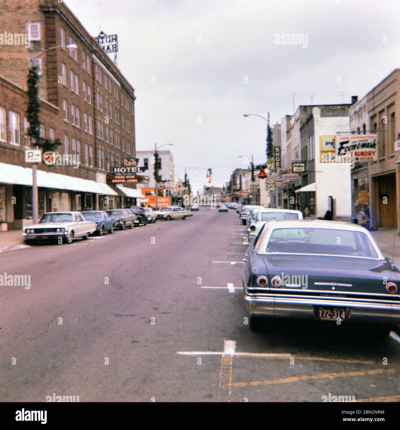 Parked cars on a city street in Portage, WI in late 1966, Ram Hotel on