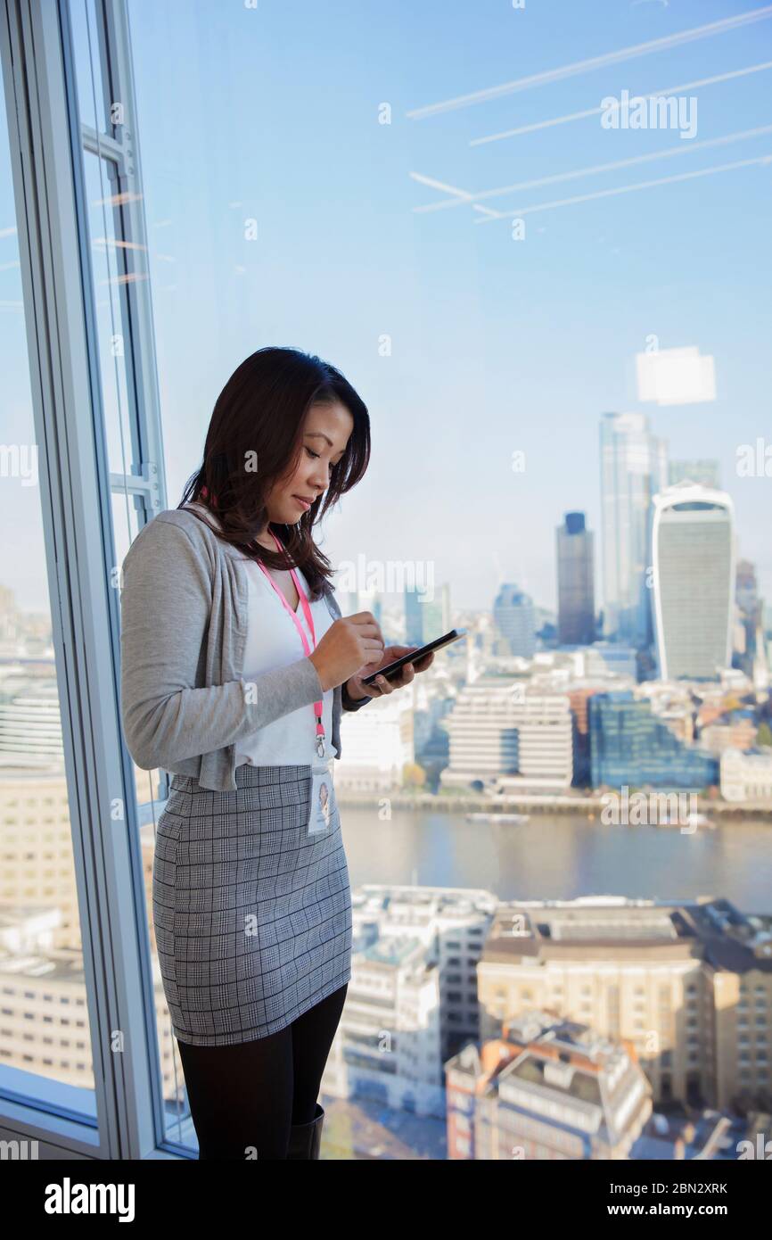 Businesswoman using digital tablet at urban highrise office window Stock Photo