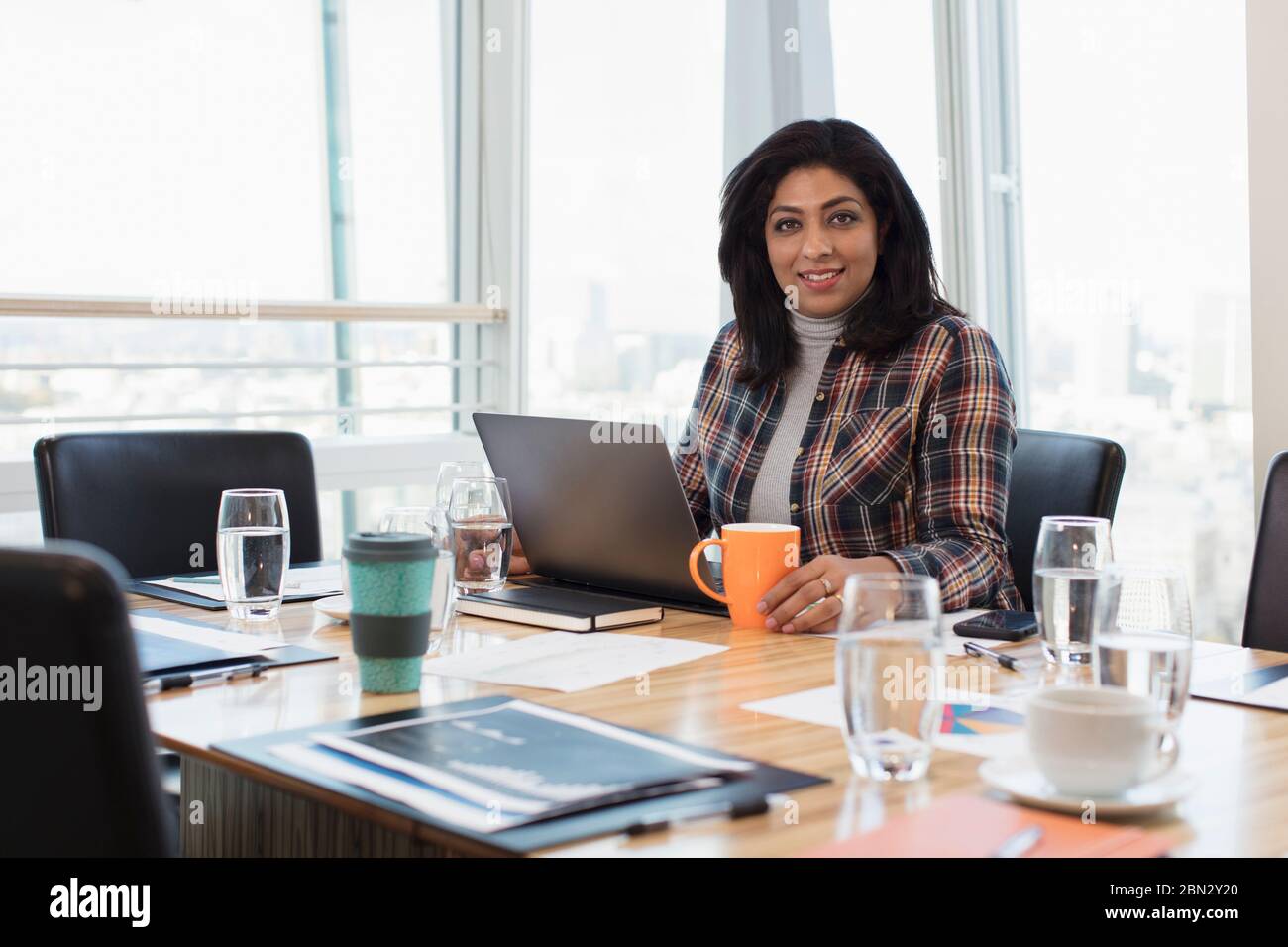 Portrait confident businesswoman using laptop at conference room table Stock Photo