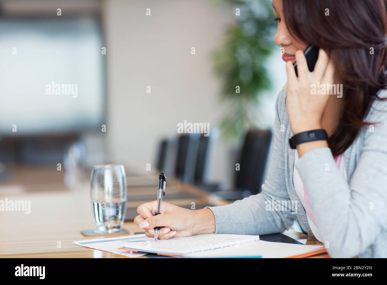 Businesswoman talking on smart phone and doing paperwork Stock Photo
