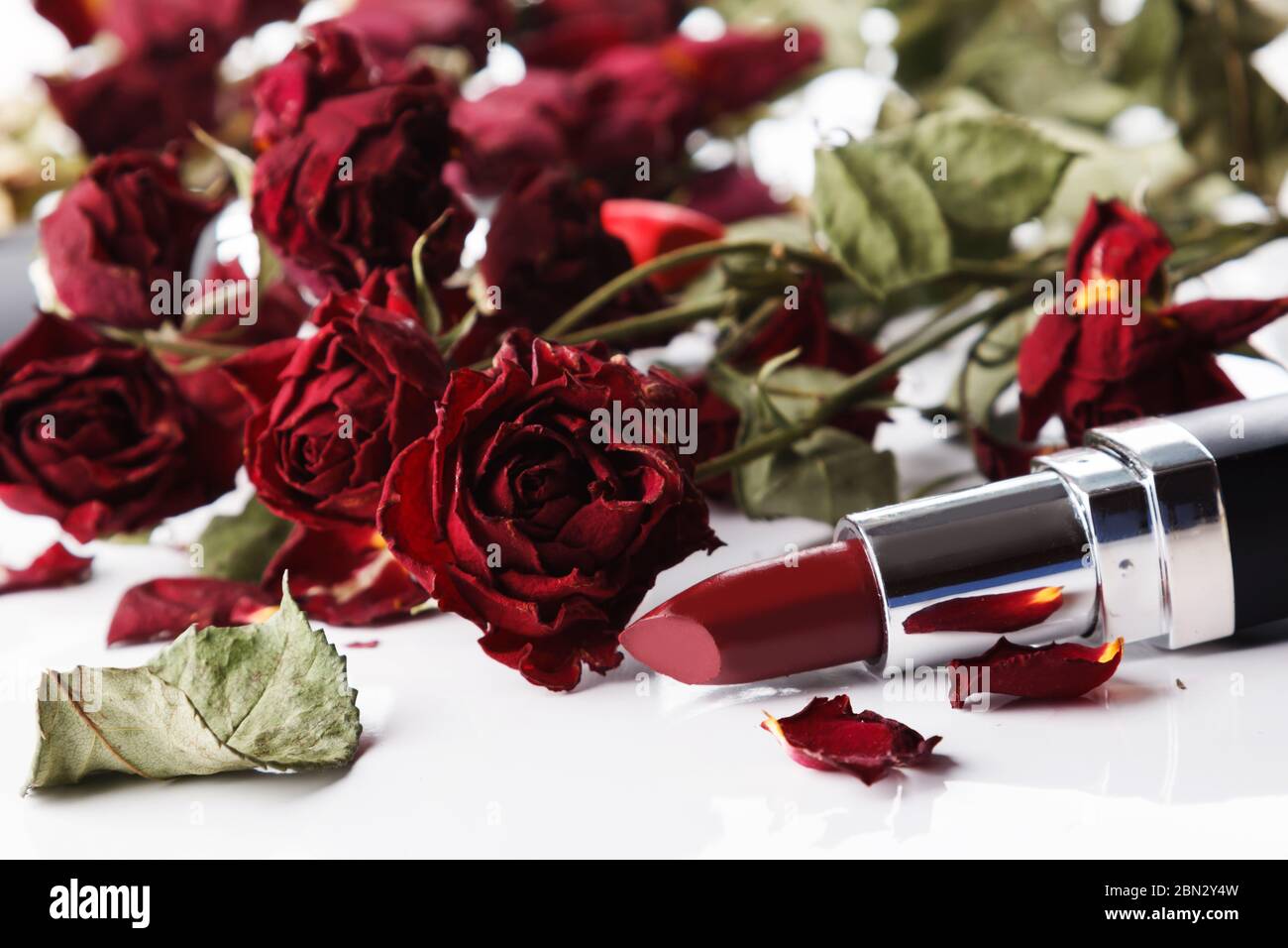 Close up of lipstick and dried rose flowers Stock Photo