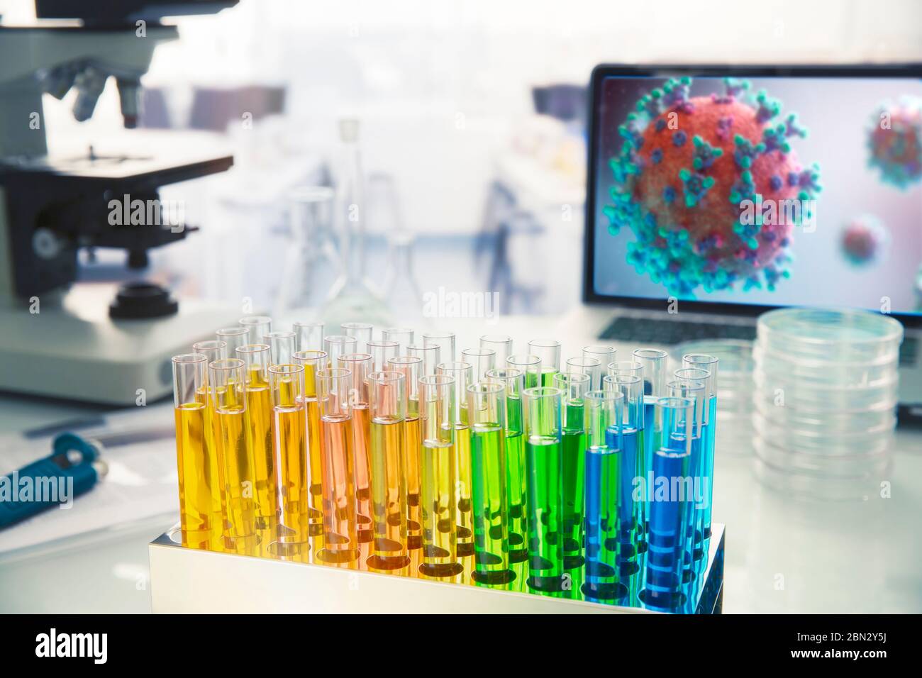 Multicolor vials on laboratory table next to coronavirus on screen Stock Photo