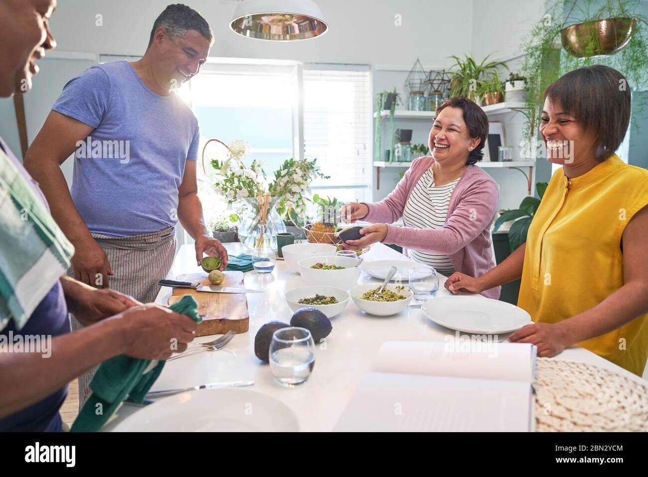 Happy mature couples cooking and eating in kitchen Stock Photo