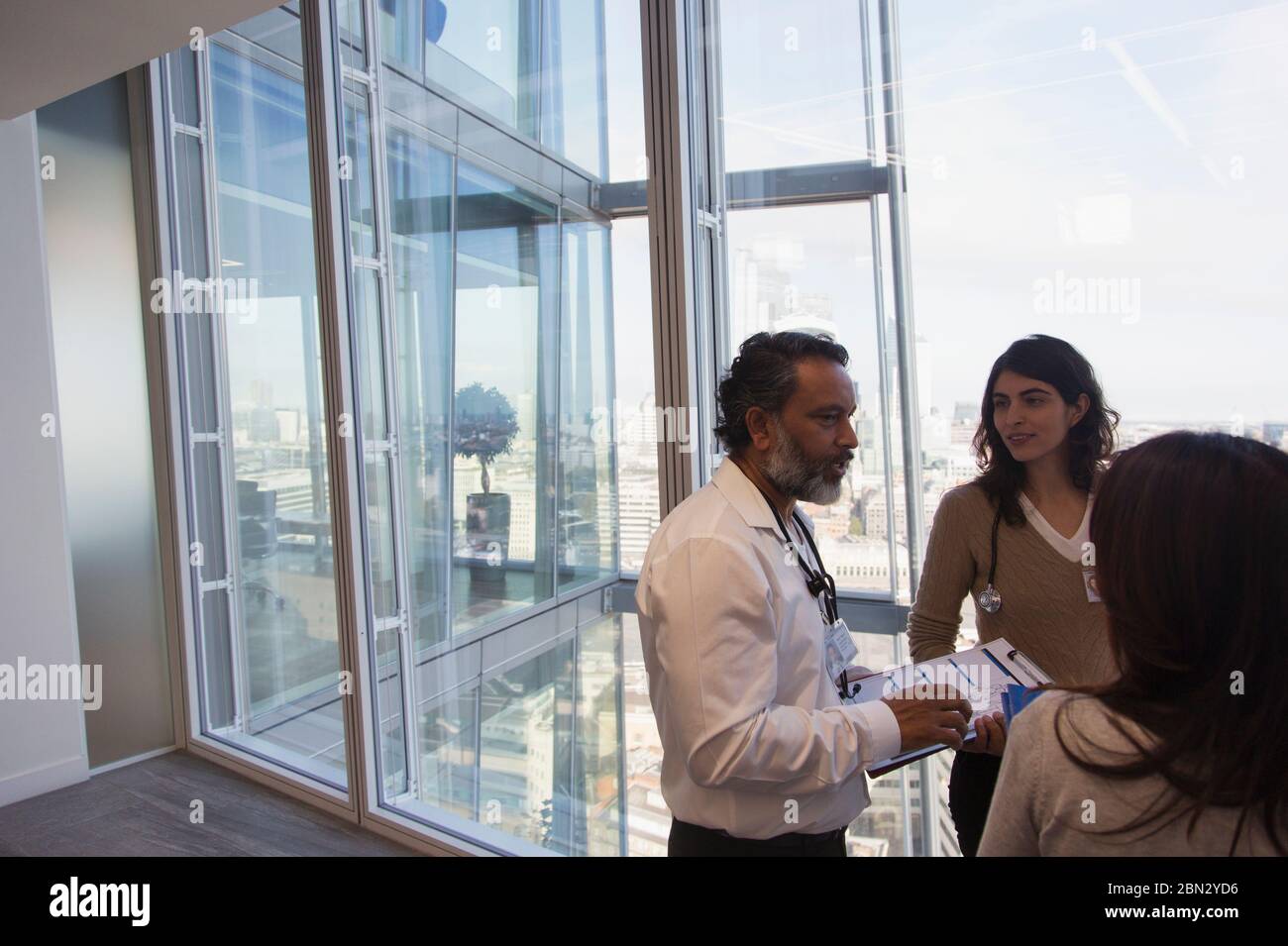 Business people talking at urban highrise office window Stock Photo