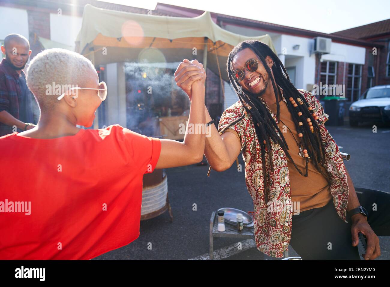 Happy friends high fiving in parking lot Stock Photo