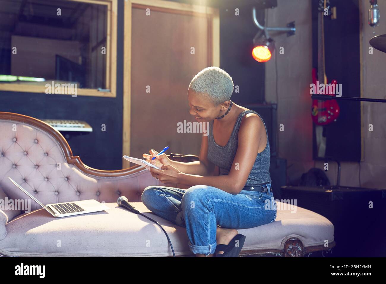 Female musician song writing on chaise lounge Stock Photo