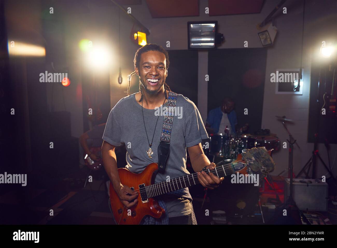 Portrait confident male musician playing guitar in recording studio Stock Photo