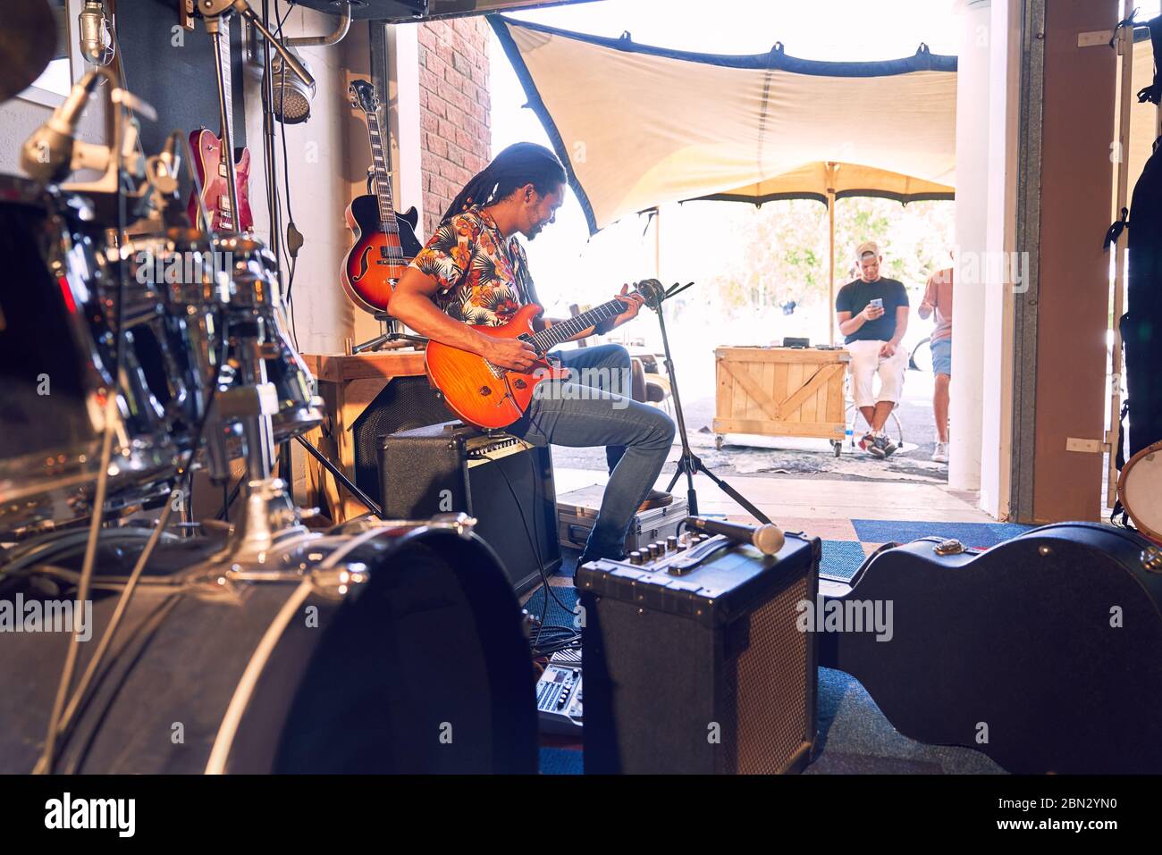Male musician practicing electric guitar in garage recording studio