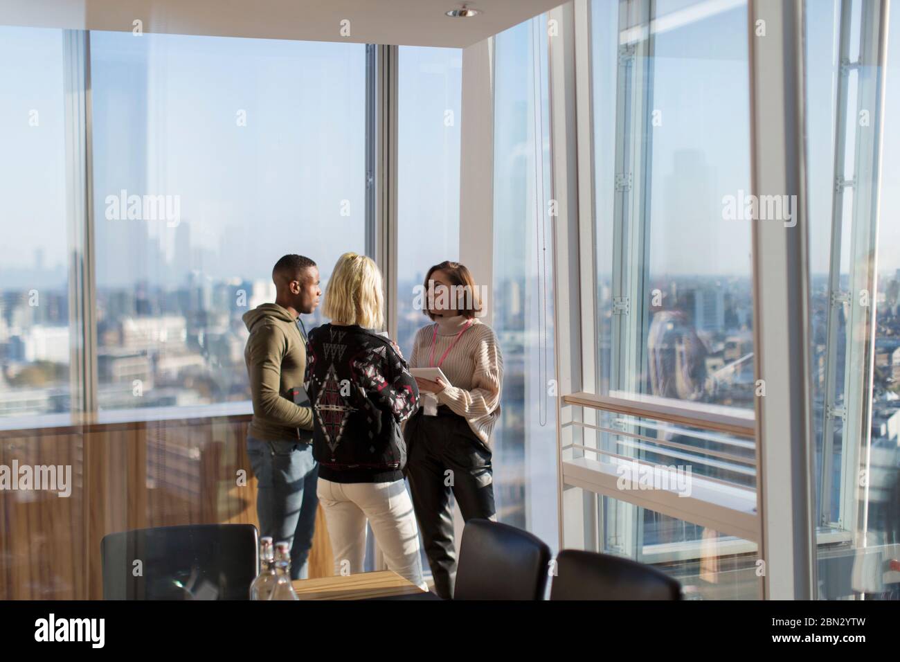 Business people talking at sunny highrise office window Stock Photo