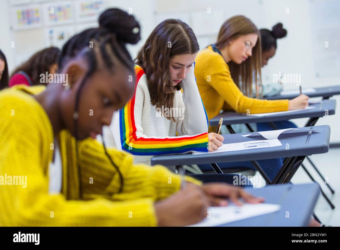 Focused high school girl students taking exam at desks in classroom Stock Photo