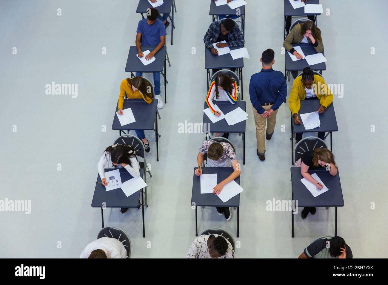 High school teacher supervising students taking exam at desks Stock Photo