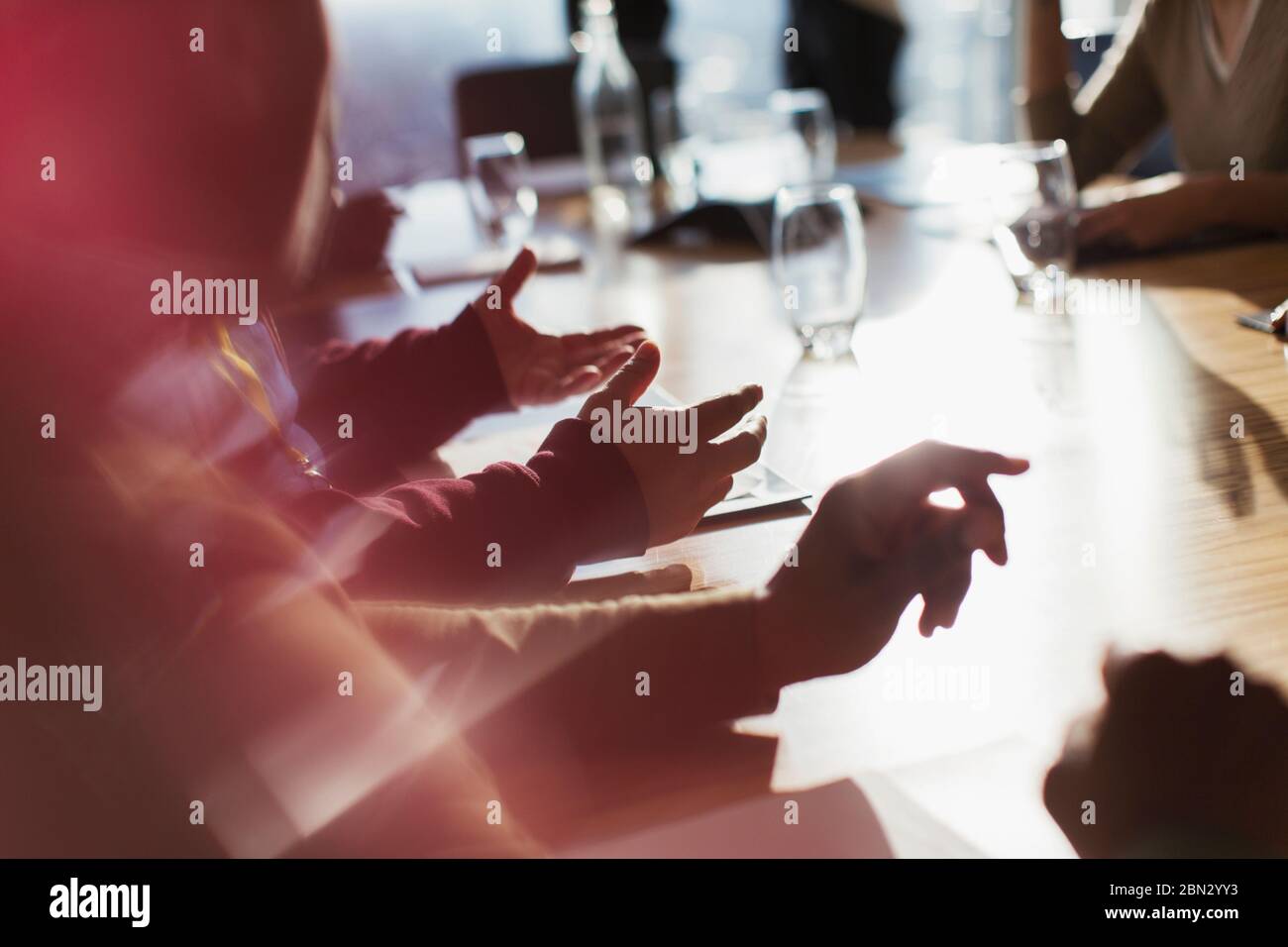 Business people gesturing in sunny conference room meeting Stock Photo