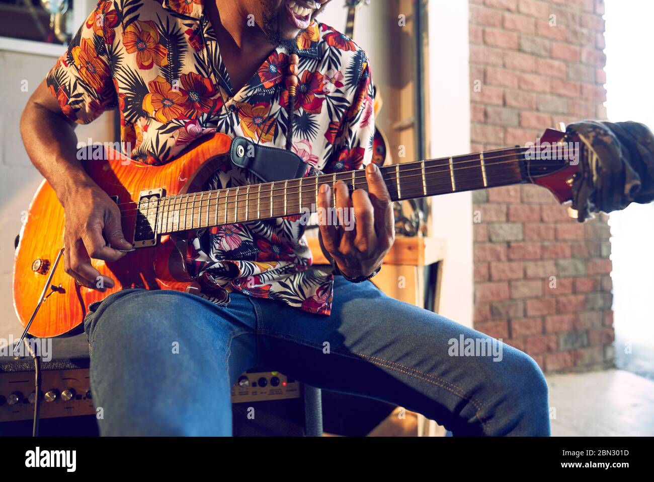 Male musician playing electric guitar in garage Stock Photo