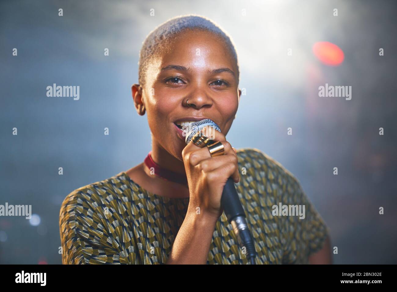 Portrait happy young female musician singing into microphone Stock Photo