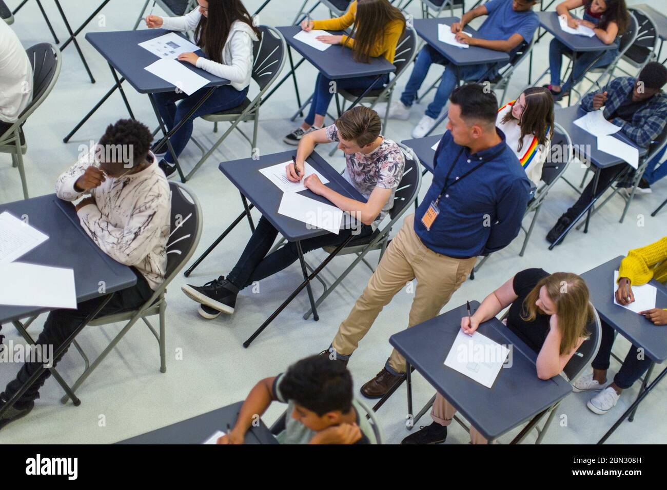 Teacher supervising high school students taking exam at desks Stock Photo