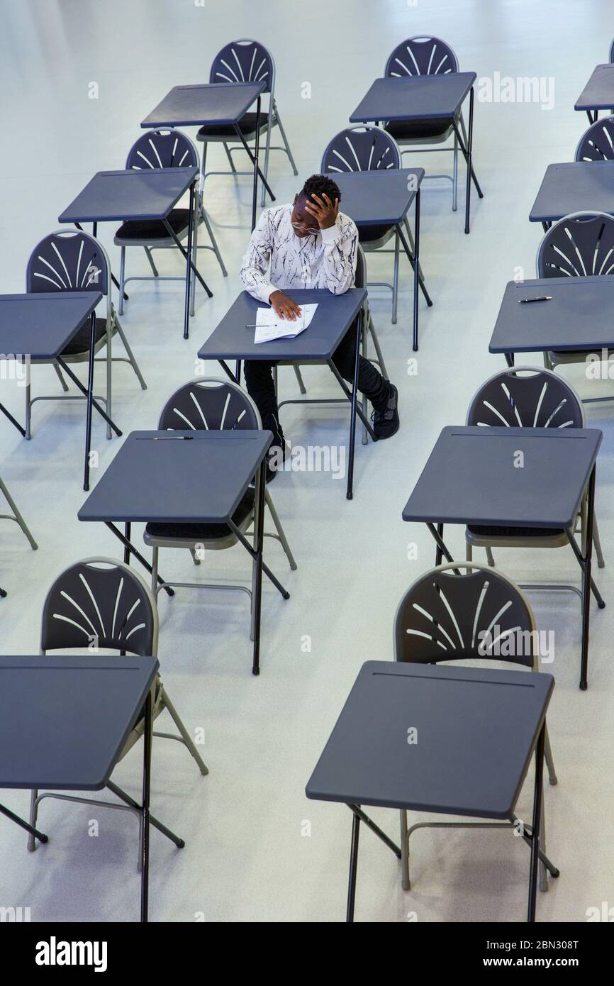Dedicated high school boy student taking exam at desk in classroom Stock Photo