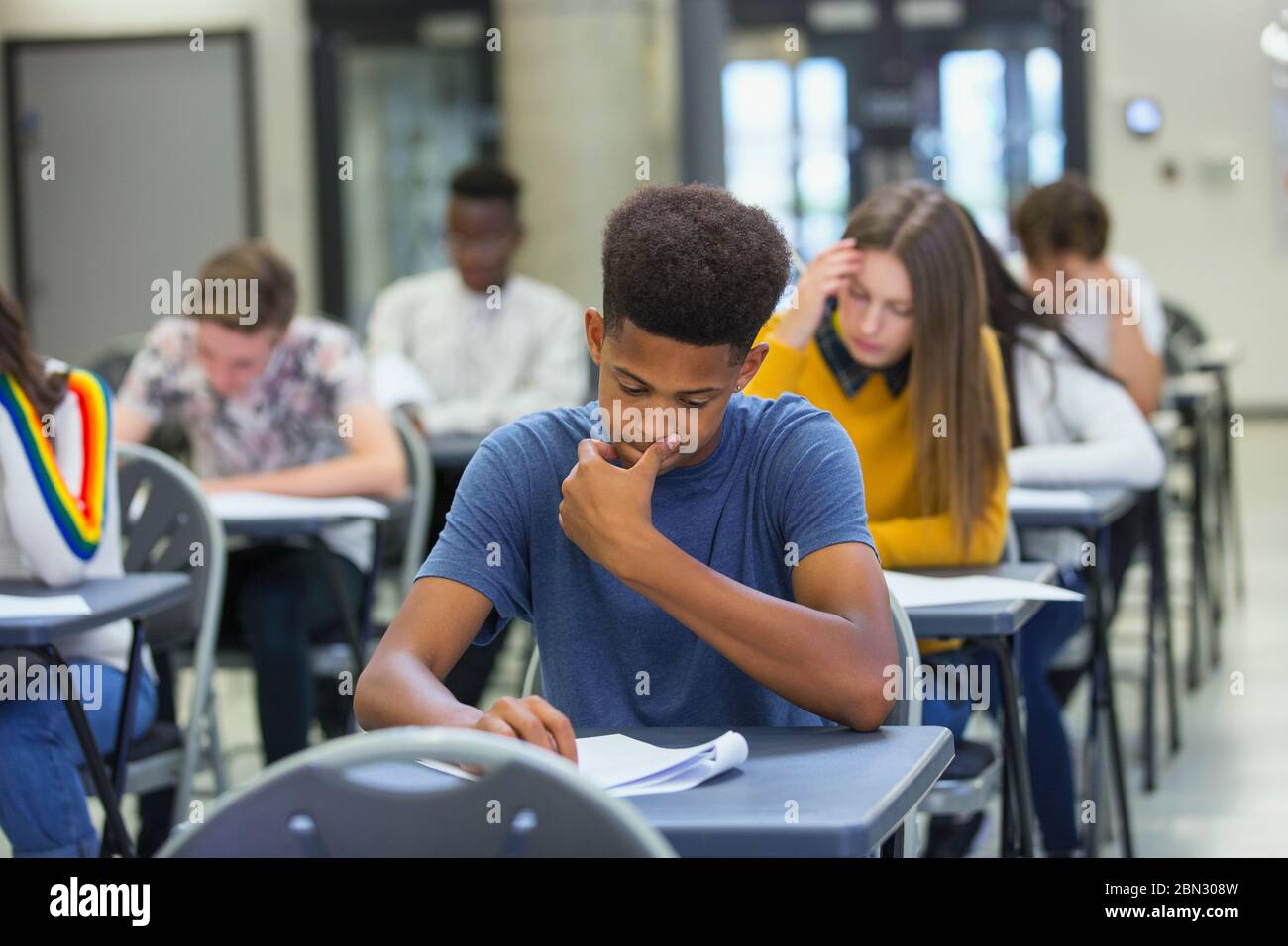 Focused high school boy student taking exam at desk in classroom Stock Photo