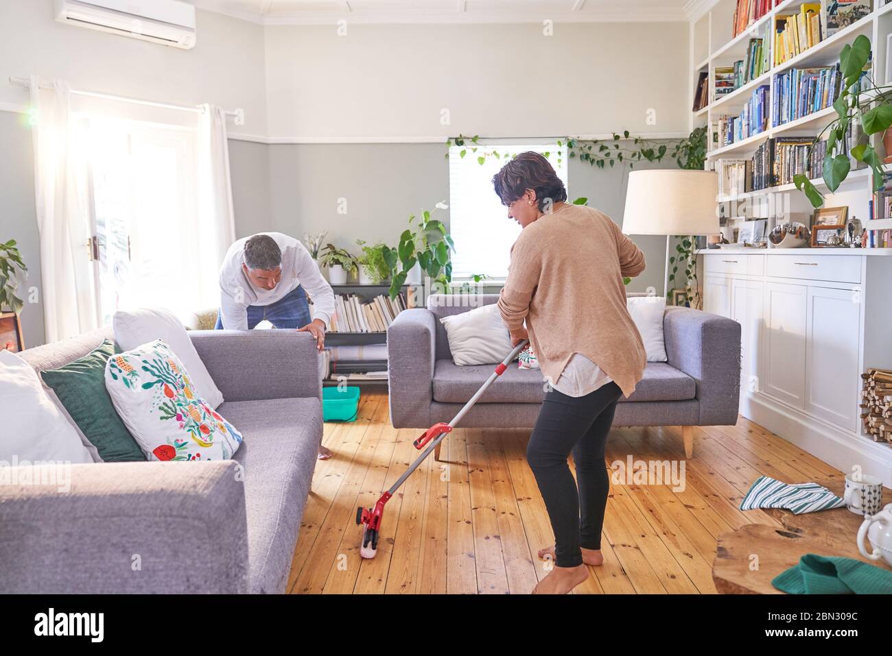 Mature couple mopping and cleaning living room Stock Photo