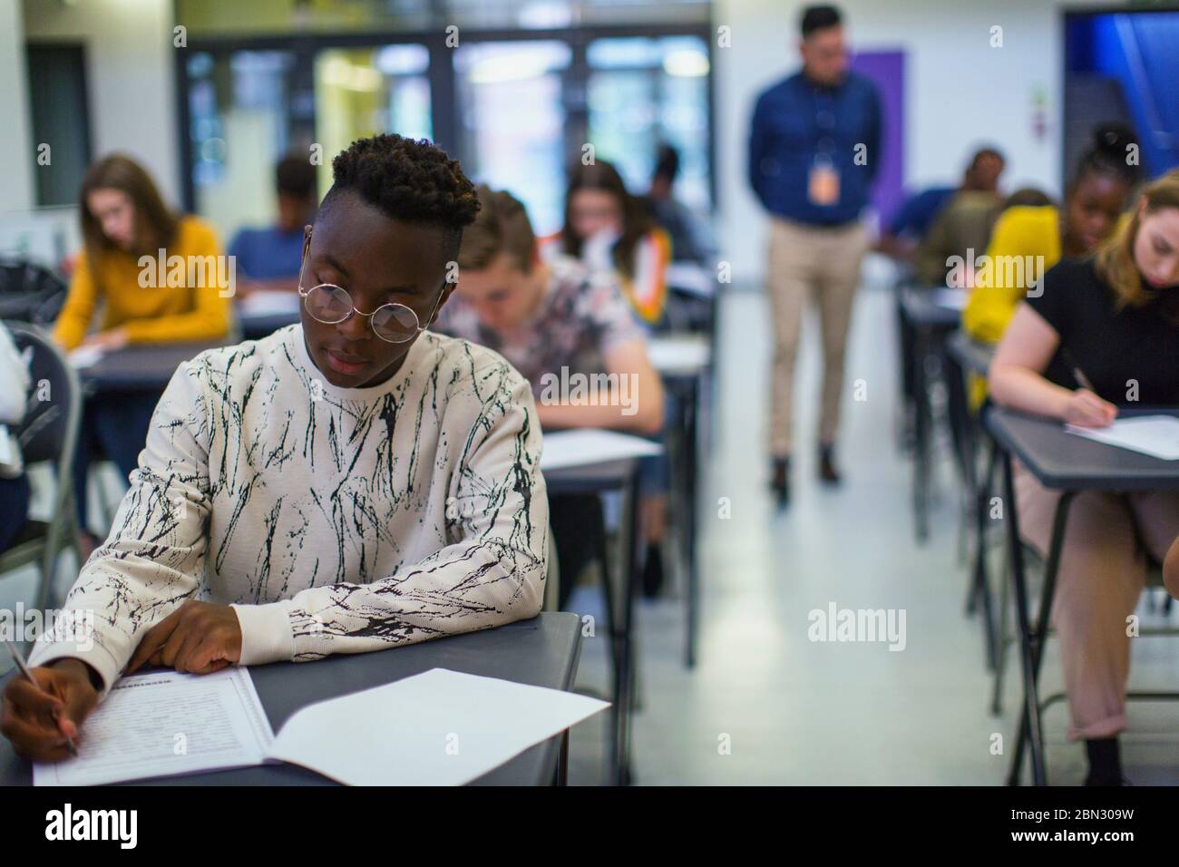 Focused high school boy student taking exam at desk Stock Photo