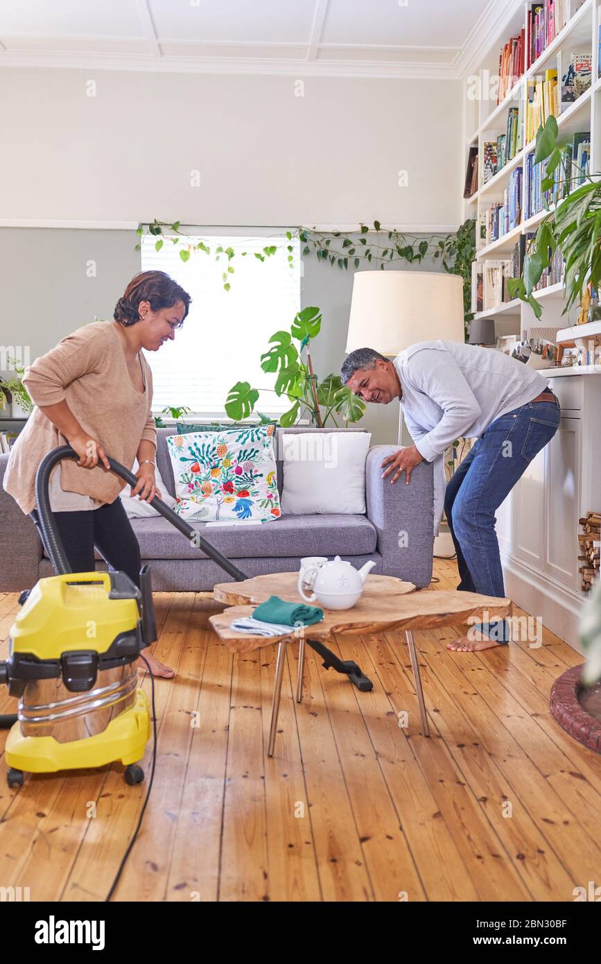 Mature couple vacuuming and cleaning living room Stock Photo