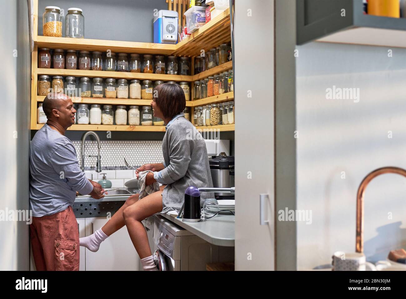 Couple talking and doing dishes in kitchen Stock Photo