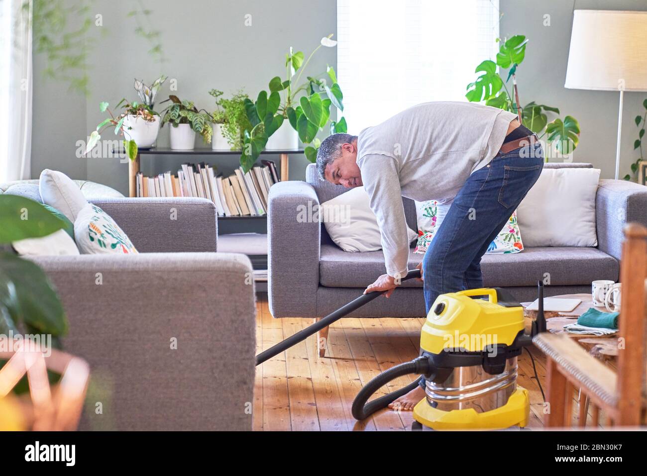 Mature man vacuuming living room Stock Photo