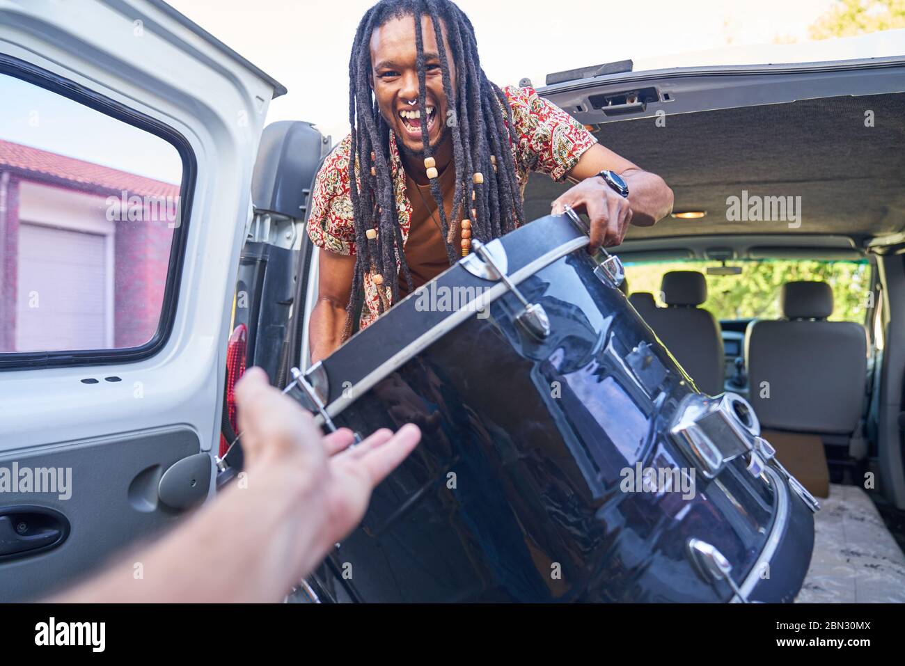 Happy male musician loading drum into van Stock Photo