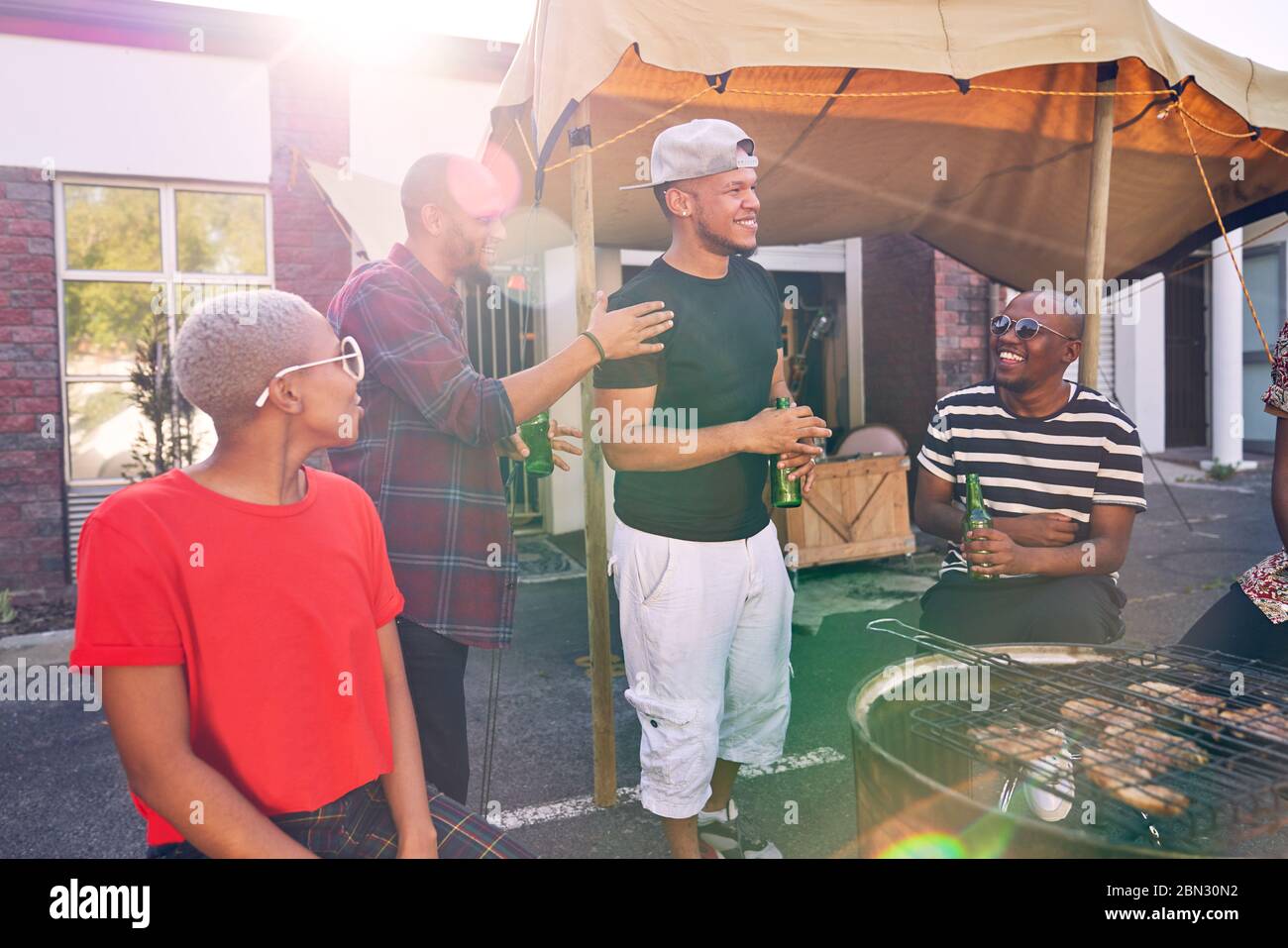 Friends hanging out and enjoying barbecue in sunny parking lot Stock Photo