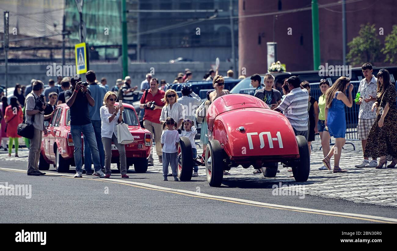 Moscow, Russia, viewers look at vintage cars participating in a motor rally Gorkyclassic around Moscow with interest, stylized Stock Photo