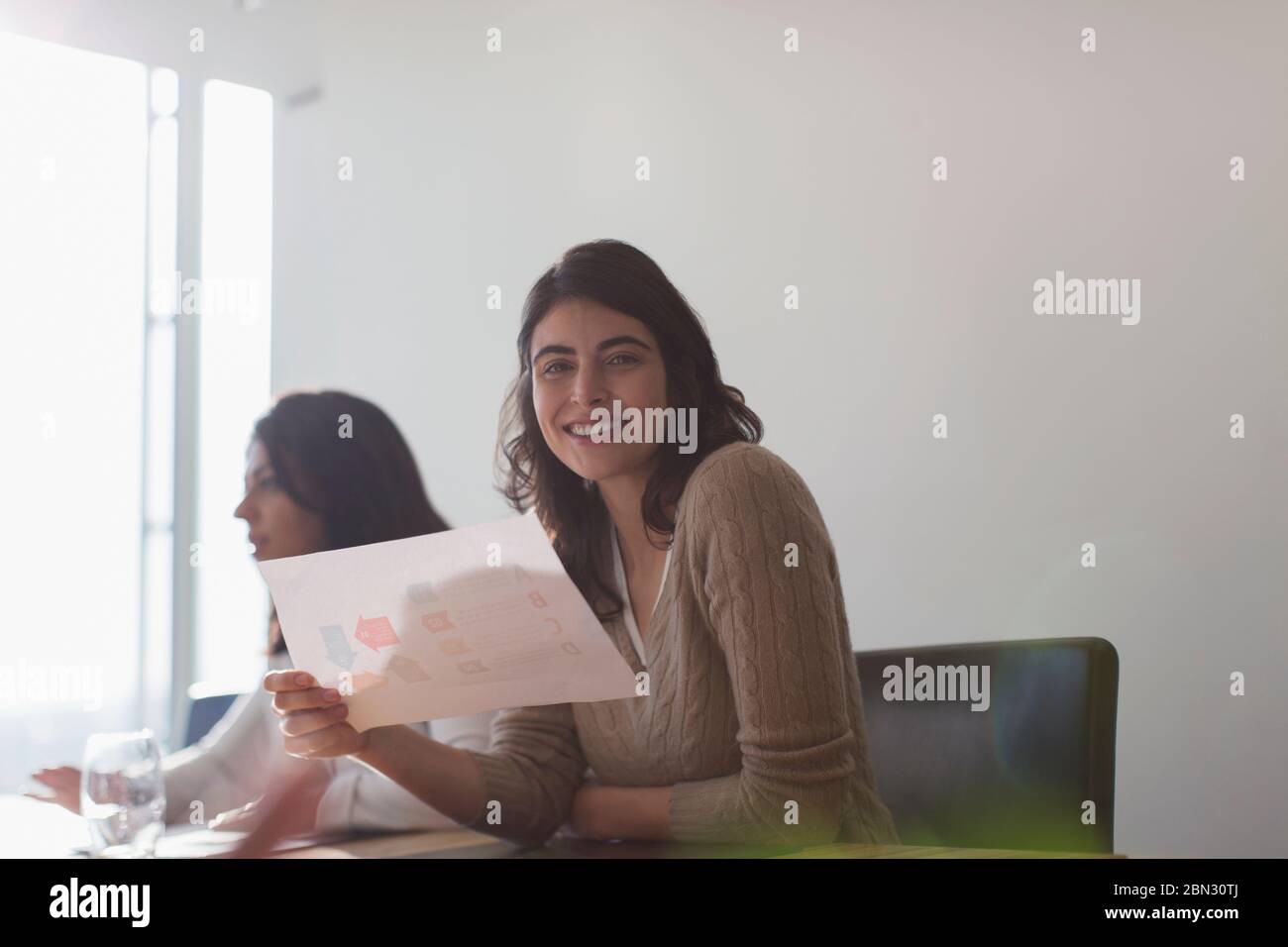 Portrait confident happy businesswoman with paperwork in office Stock Photo
