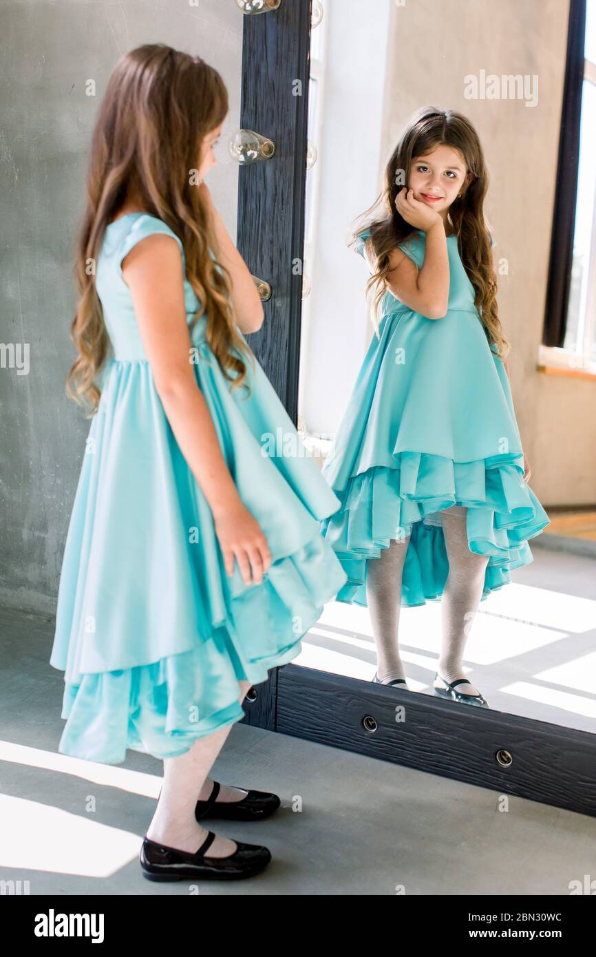 The lovely little girl posing in a beautiful blue dress is posing ...