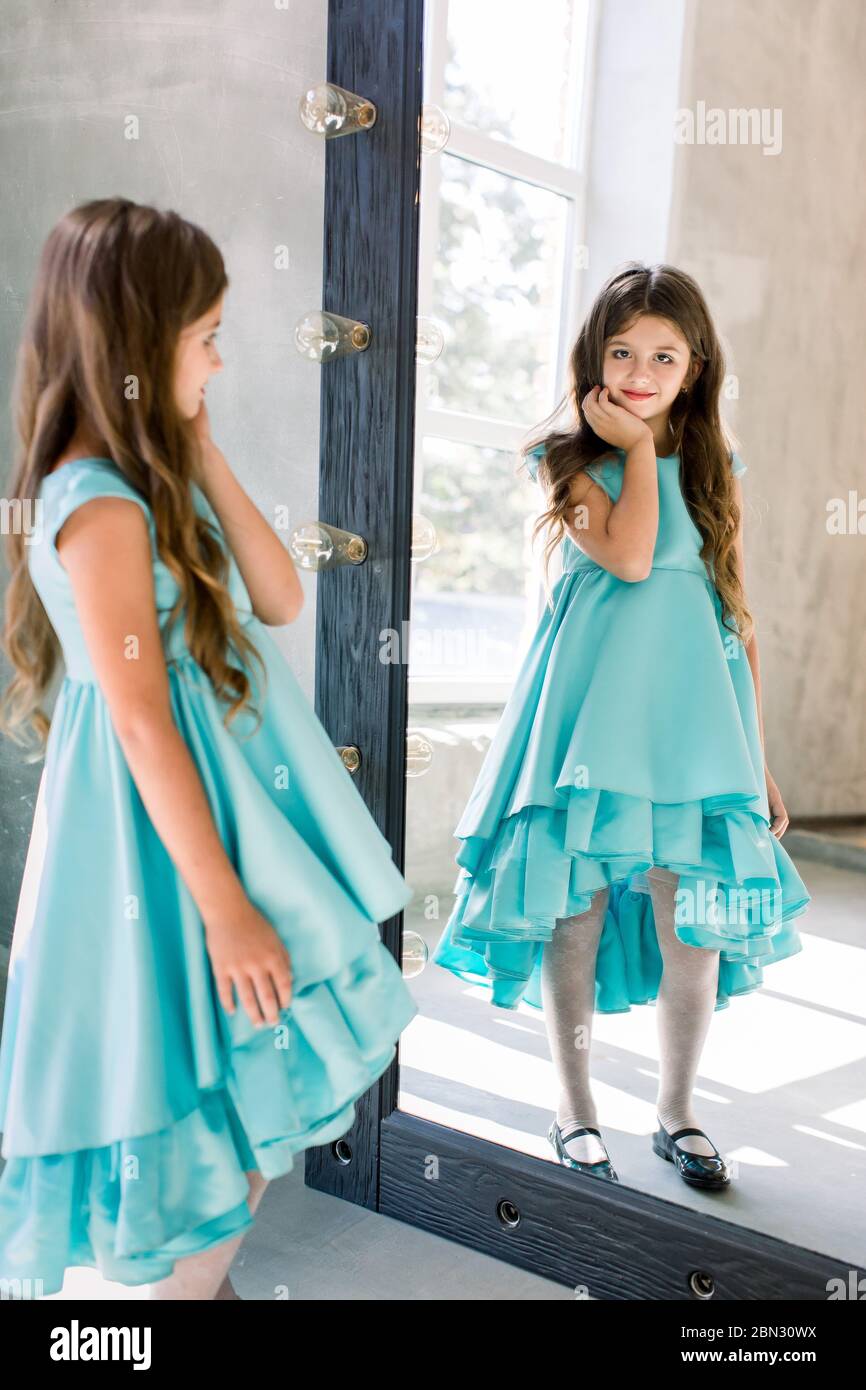 The lovely little girl posing in a beautiful blue dress is posing ...