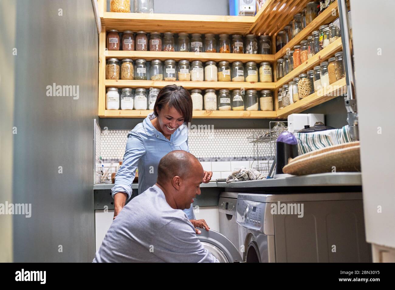 Happy couple doing laundry in kitchen Stock Photo