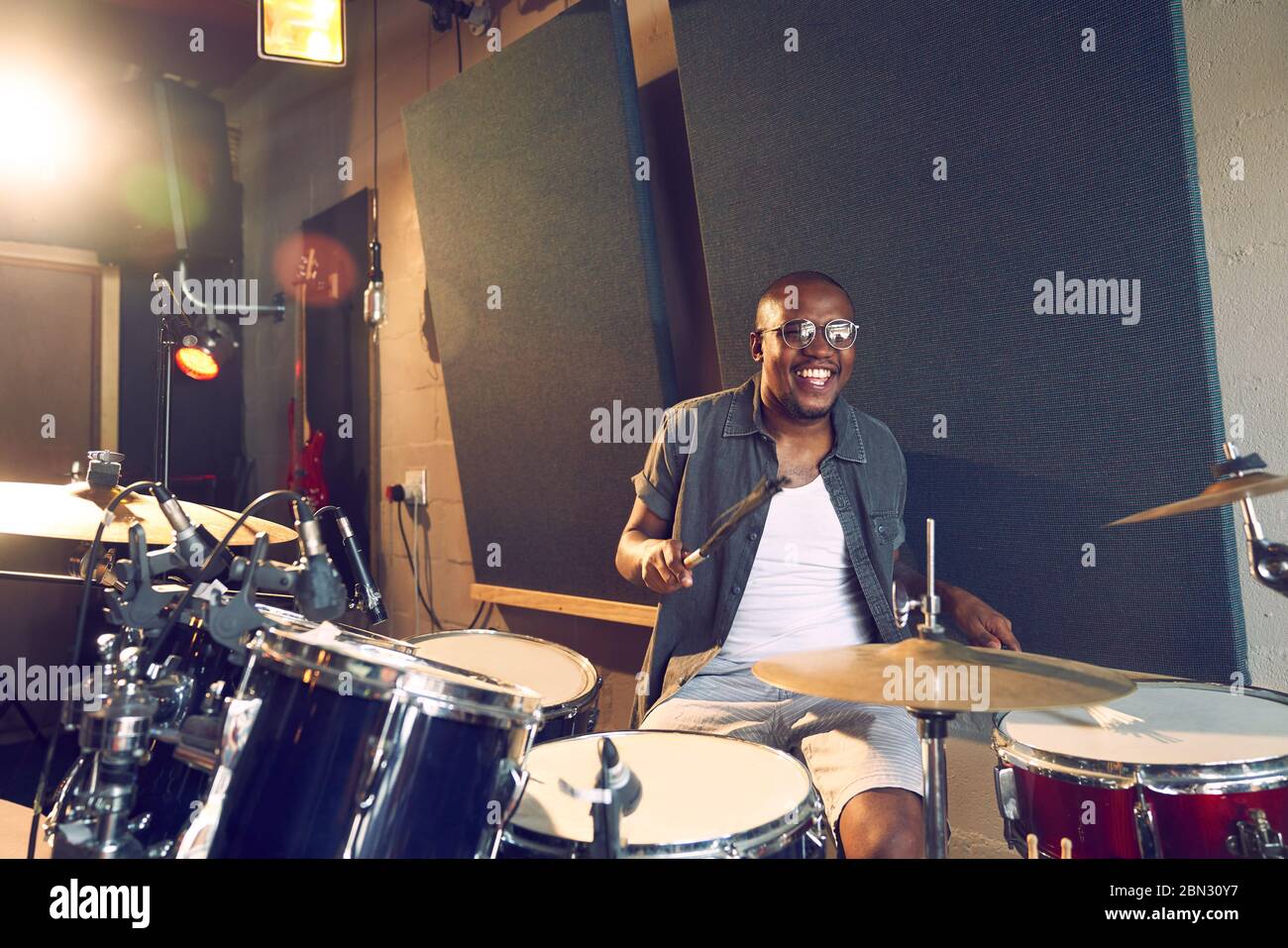 Happy male musician playing drums in recording studio Stock Photo